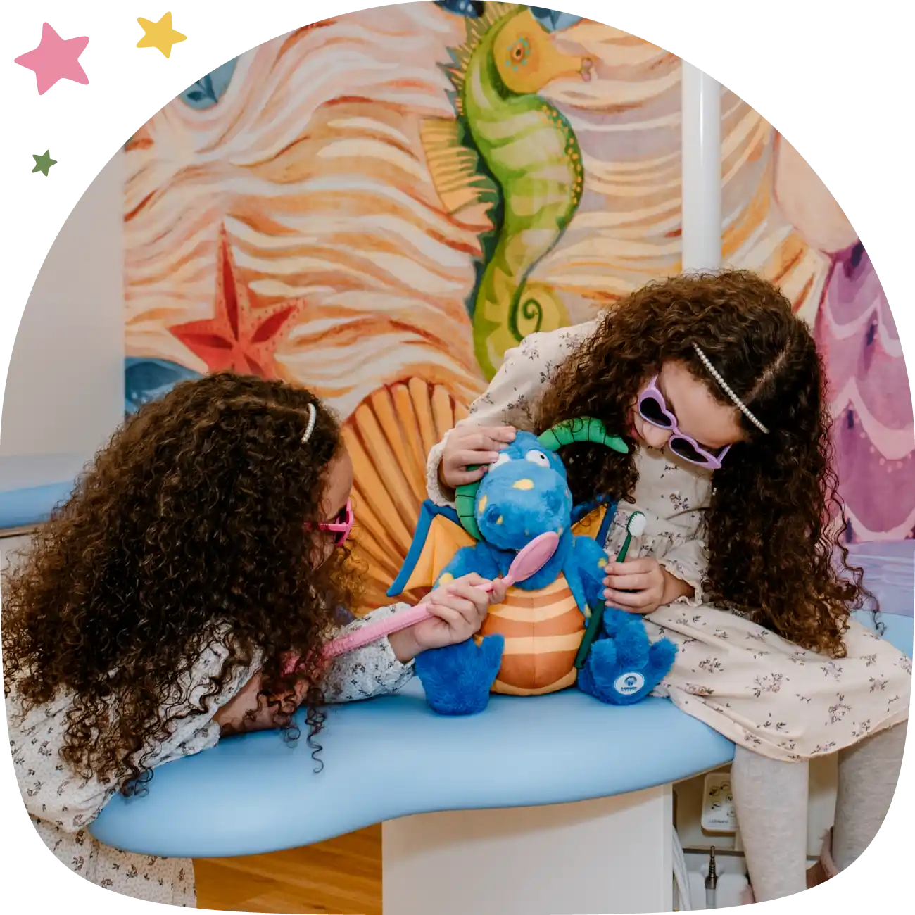 Zwei Kinder spielen mit Plüschtier und Zahnbürste in Behandlungszimmer